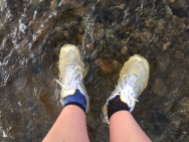 Looking down at feet wearing trainers, submerged in floodwater